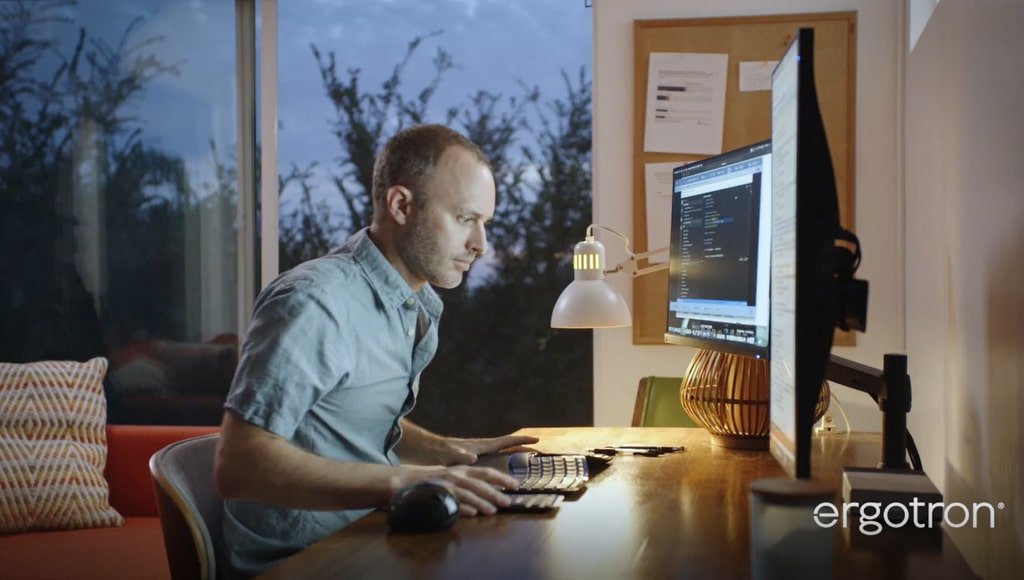 Seorang pria menggunakan Ergotron LX Desk Dual Monitor Arm agar mudah mengatur posisi monitornya