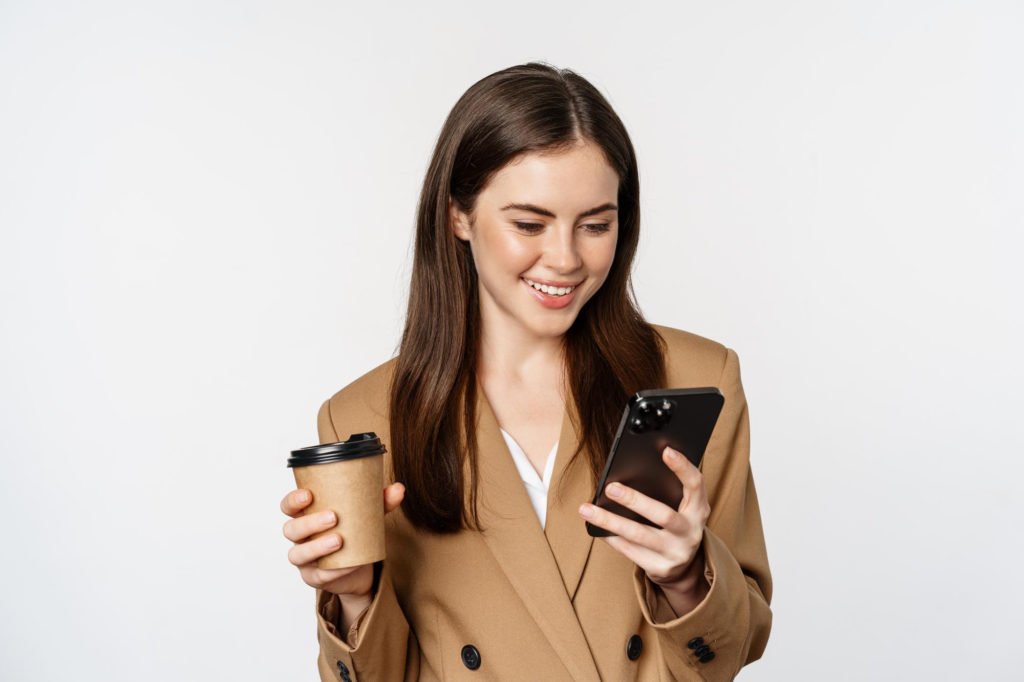 Portrait saleswoman corporate woman drinking takeaway coffee reading smartphone looking mo 1024x682